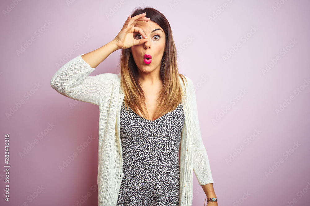 Young beautiful woman standing over pink isolated background doing ok gesture shocked with surprised face, eye looking through fingers. Unbelieving expression. Young beautiful woman standing over pink isolated background doing ok gesture shocked with surprised face, eye looking through fingers. Unbelieving expression.