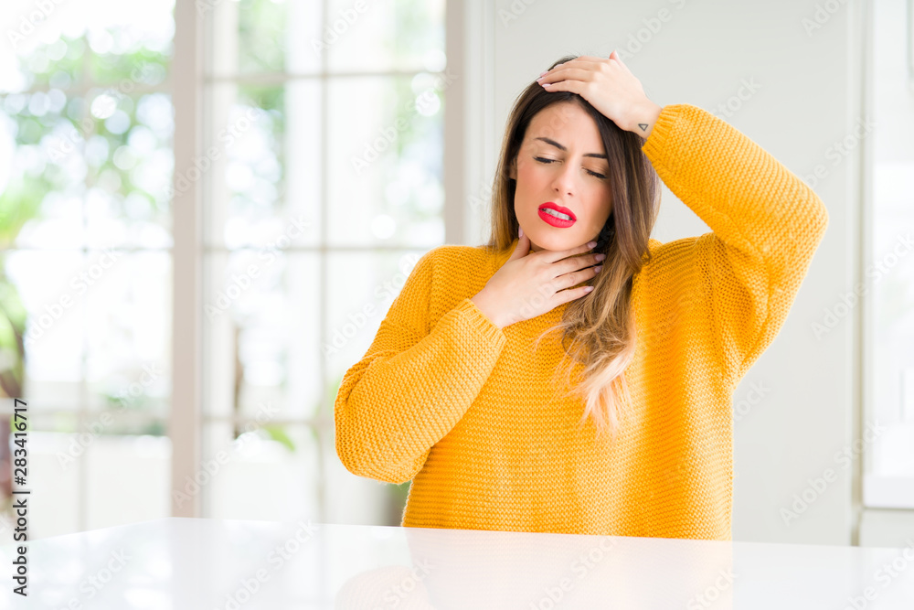 Young beautiful woman wearing winter sweater at home Touching forehead for illness and fever, flu and cold, virus sick Young beautiful woman wearing winter sweater at home Touching forehead for illness and fever, flu and cold, virus sick
