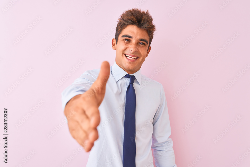 Young handsome businessman wearing shirt and tie standing over isolated pink background smiling friendly offering handshake as greeting and welcoming. Successful business. Young handsome businessman wearing shirt and tie standing over isolated pink background smiling friendly offering handshake as greeting and welcoming. Successful business.