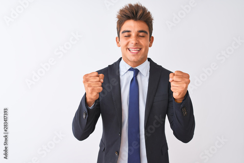 Young handsome businessman wearing suit standing over isolated white background excited for success with arms raised and eyes closed celebrating victory smiling. Winner concept.