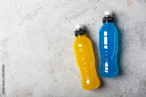 Isotonic energy drink. Bottles with blue and yellow transparent liquid, sport beverage on a gray concrete background