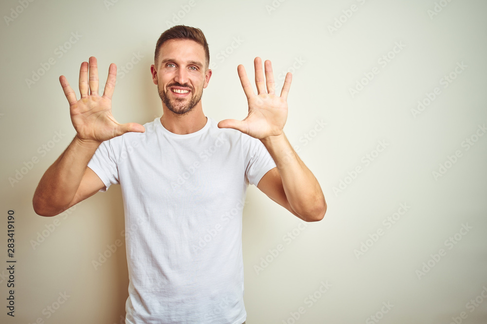 Young handsome man wearing casual white t-shirt over isolated background showing and pointing up with fingers number ten while smiling confident and happy. Young handsome man wearing casual white t-shirt over isolated background showing and pointing up with fingers number ten while smiling confident and happy.