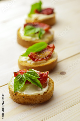 Tasty bruschetta with sun-dried tomatoes on wooden table