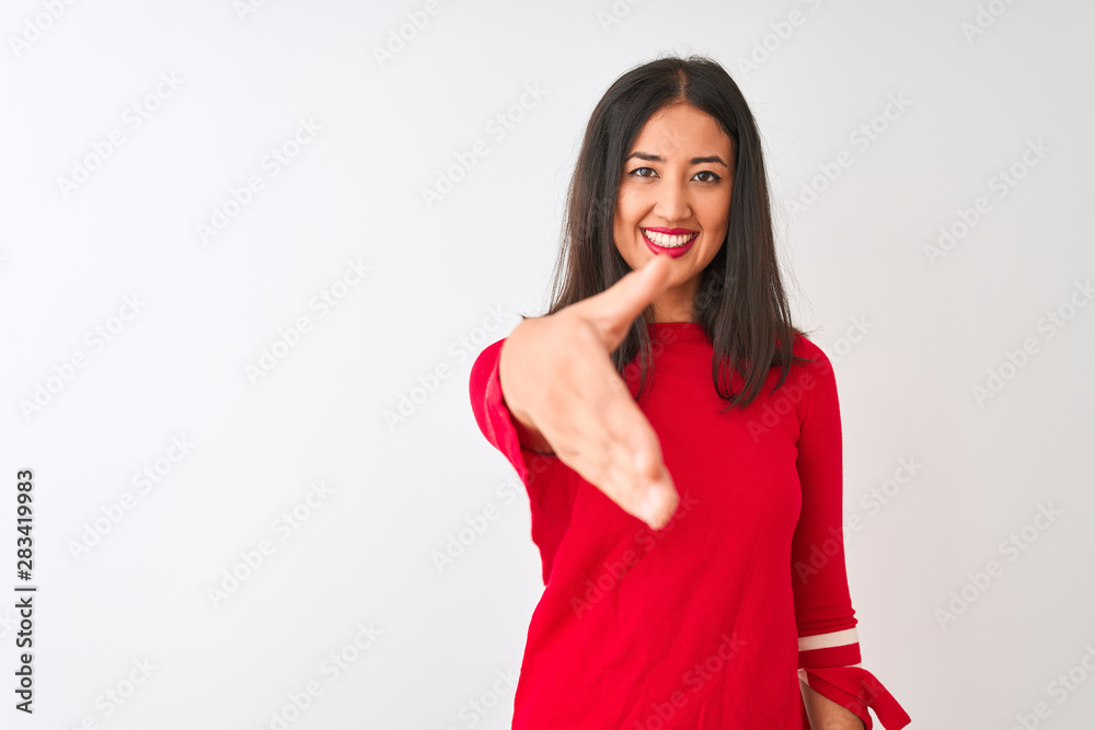 Young beautiful chinese woman wearing red dress standing over isolated white background smiling friendly offering handshake as greeting and welcoming. Successful business. Young beautiful chinese woman wearing red dress standing over isolated white background smiling friendly offering handshake as greeting and welcoming. Successful business.