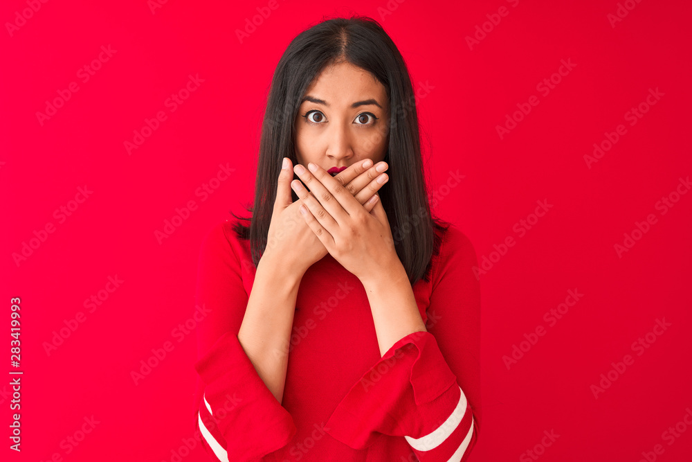 Young beautiful chinese woman wearing casual dress standing over isolated red background shocked covering mouth with hands for mistake. Secret concept. Young beautiful chinese woman wearing casual dress standing over isolated red background shocked covering mouth with hands for mistake. Secret concept.