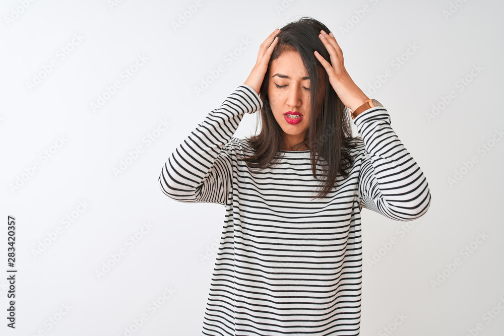 Young beautiful chinese woman wearing striped t-shirt standing over isolated white background suffering from headache desperate and stressed because pain and migraine. Hands on head. Young beautiful chinese woman wearing striped t-shirt standing over isolated white background suffering from headache desperate and stressed because pain and migraine. Hands on head.