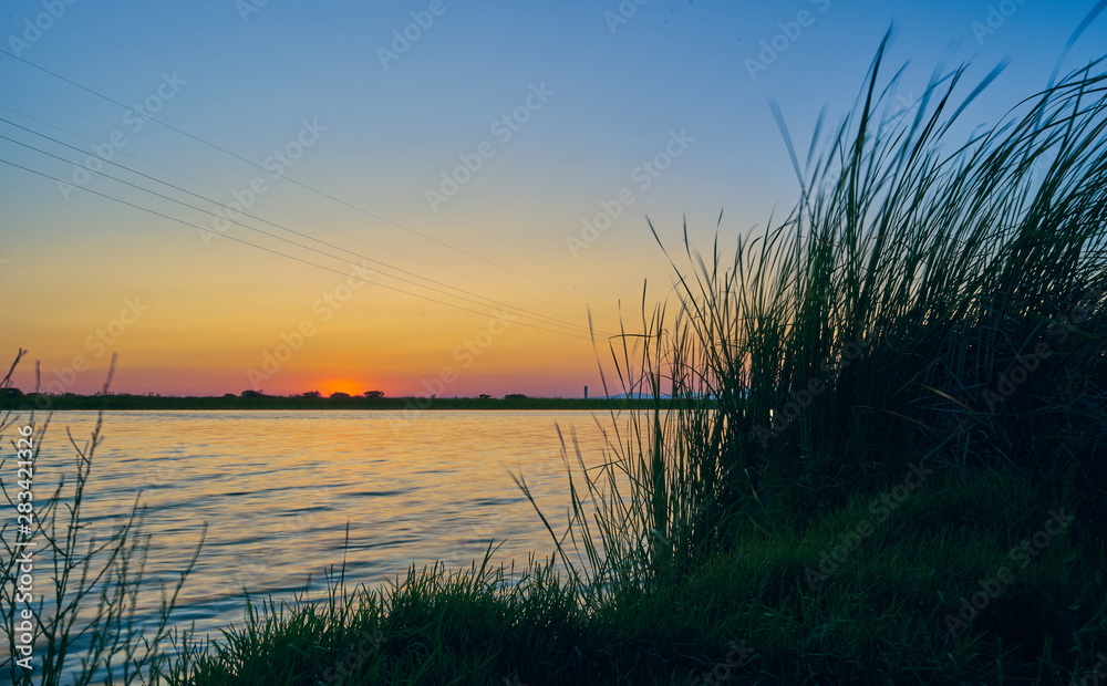 Sunset in a landscape with lake, trees and light towers. Extremadura. Spain Sunset in a landscape with lake, trees and light towers. Extremadura. Spain