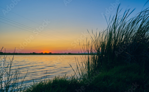 Sunset in a landscape with lake  trees and light towers. Extremadura. Spain