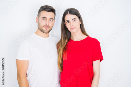 Young beautiful couple together over white isolated background with serious expression on face. Simple and natural looking at the camera.