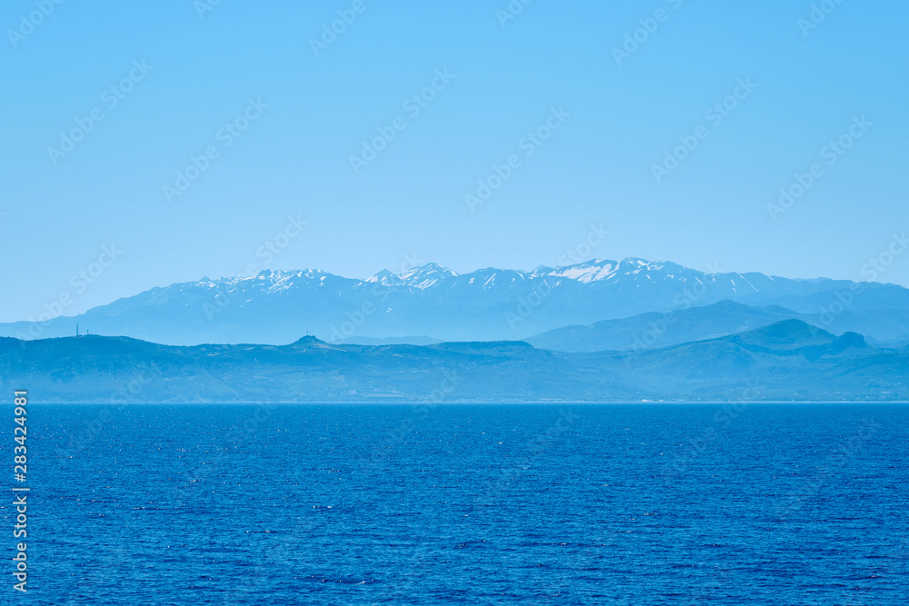 Foggy sea coast of Kolymbari, Crete, Greece with mountains and clear blue sky on a background.