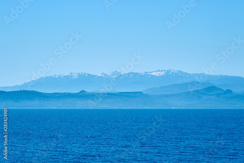 Foggy sea coast of Kolymbari, Crete, Greece with mountains and clear blue sky on a background.