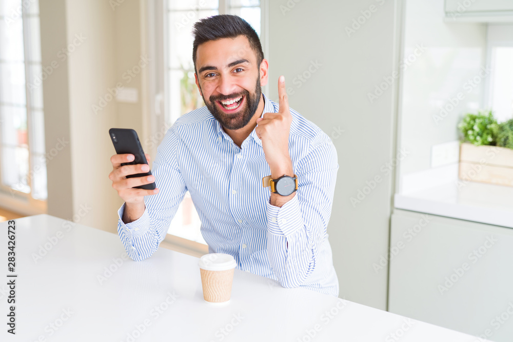 Handsome hispanic business man drinking coffee and using smartphone surprised with an idea or question pointing finger with happy face, number one Handsome hispanic business man drinking coffee and using smartphone surprised with an idea or question pointing finger with happy face, number one