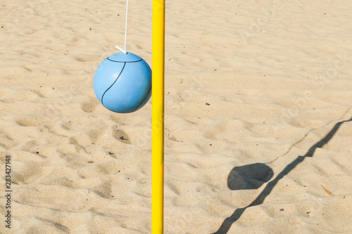 Photography A blue ball and yellow pole on the beach for playing tetherball.