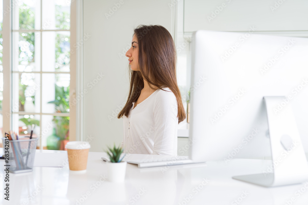 Beautiful young woman working using computer looking to side, relax profile pose with natural face with confident smile. Beautiful young woman working using computer looking to side, relax profile pose with natural face with confident smile.