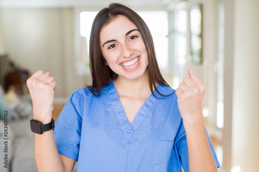 Beautiful young nurse woman at the clinic celebrating surprised and amazed for success with arms raised and open eyes. Winner concept. Beautiful young nurse woman at the clinic celebrating surprised and amazed for success with arms raised and open eyes. Winner concept.