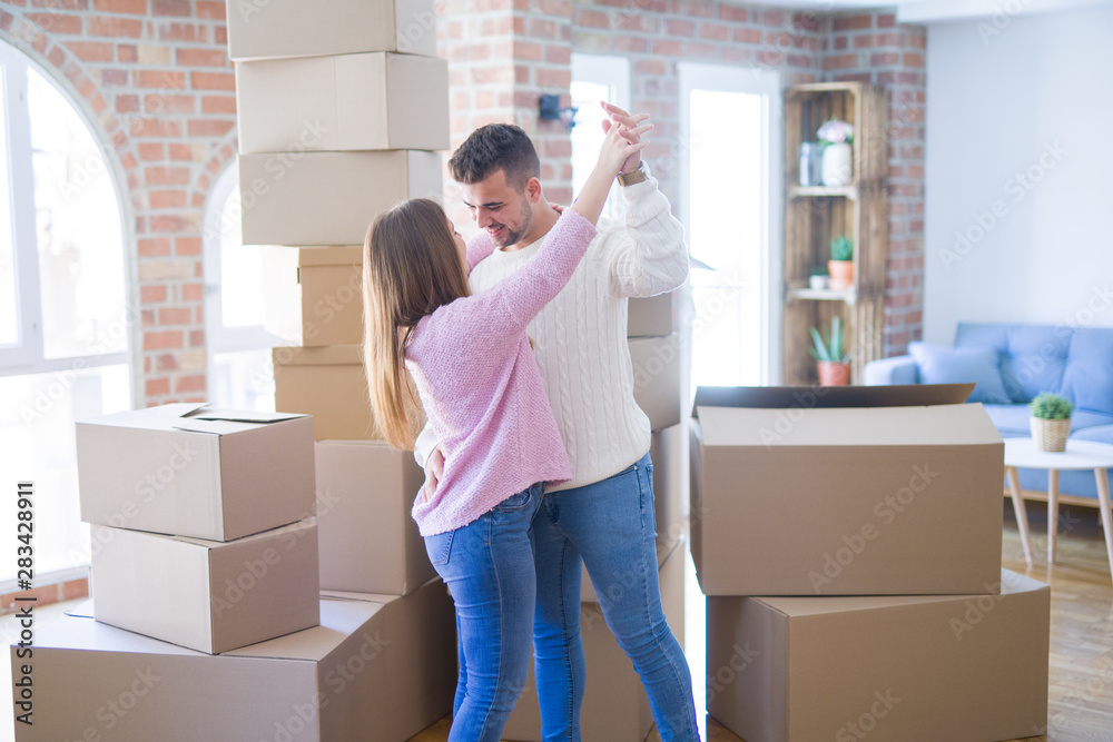 Young beautiful couple in love celebrating dancing moving to a new home, smiling very happy for new apartment Young beautiful couple in love celebrating dancing moving to a new home, smiling very happy for new apartment