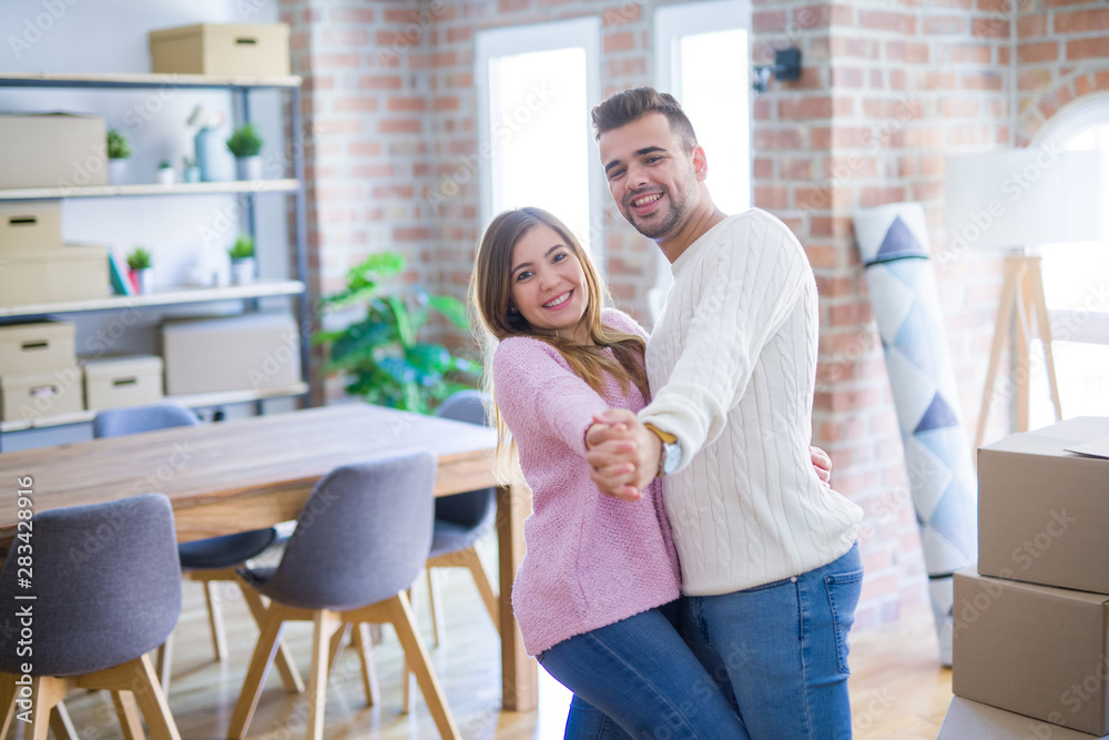 Young beautiful couple in love celebrating dancing moving to a new home, smiling very happy for new apartment Young beautiful couple in love celebrating dancing moving to a new home, smiling very happy for new apartment