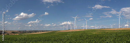 Panoramic view of Wind turbines on the fields under a blue sky with some clouds photo