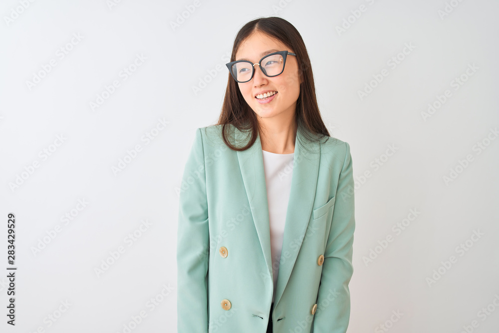 Chinese businesswoman wearing elegant jacket and glasses over isolated white background looking away to side with smile on face, natural expression. Laughing confident.