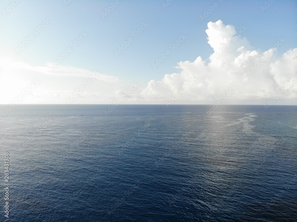 Still blue sea ocean with sky and clouds in background