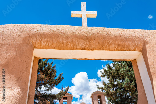 Ranchos de Taos closeup of San Francisco de Asis church with cross and gate in New Mexico low angle looking up at sky photo