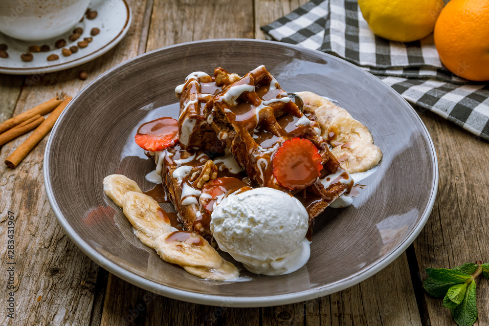 Belgian waffles on plate with ice cream and berries and banana on wooden background Belgian waffles on plate with ice cream and berries and banana on wooden background