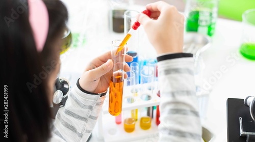 Kid learning science in chemical laboratory.
