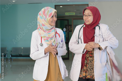 two female asian hijab doctor's discuss and studying about patient's document on the loby hall photo