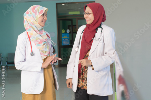 two female asian hijab doctor's discuss and studying about patient's document on the loby hall photo