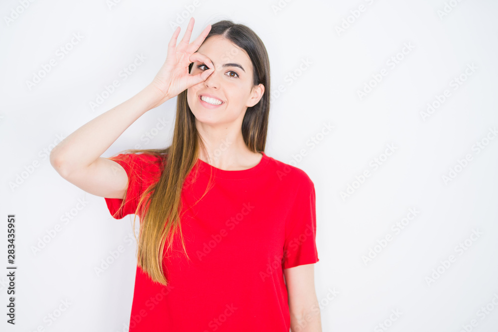 Young beautiful woman wearing casual red t-shirt over white isolated background doing ok gesture with hand smiling, eye looking through fingers with happy face. Young beautiful woman wearing casual red t-shirt over white isolated background doing ok gesture with hand smiling, eye looking through fingers with happy face.