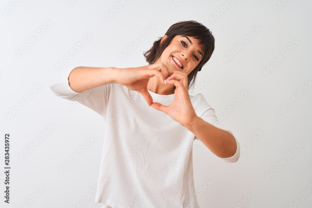 Young beautiful woman wearing casual t-shirt standing over isolated white background smiling in love showing heart symbol and shape with hands. Romantic concept. Young beautiful woman wearing casual t-shirt standing over isolated white background smiling in love showing heart symbol and shape with hands. Romantic concept.