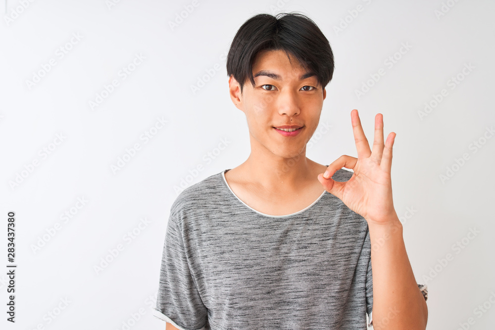 Young chinese man wearing casual t-shirt standing over isolated white background doing ok sign with fingers, excellent symbol Young chinese man wearing casual t-shirt standing over isolated white background doing ok sign with fingers, excellent symbol