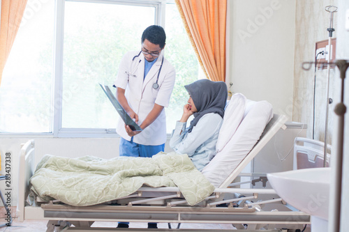 Portrait of Asian male doctor with his female patient in the hospital clinic explaining xray results photo