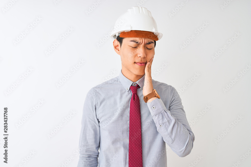Chinese architect man wearing tie and helmet standing over isolated white background touching mouth with hand with painful expression because of toothache or dental illness on teeth. Dentist concept. Chinese architect man wearing tie and helmet standing over isolated white background touching mouth with hand with painful expression because of toothache or dental illness on teeth. Dentist concept.