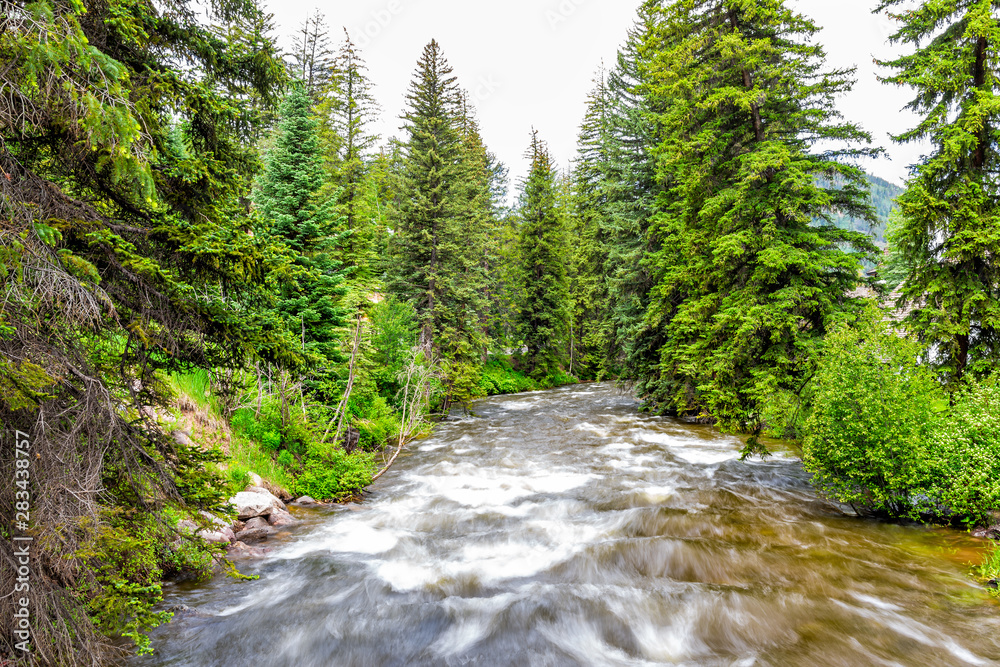 Vail resort town city in Colorado with long exposure of Gore creek river and pine trees