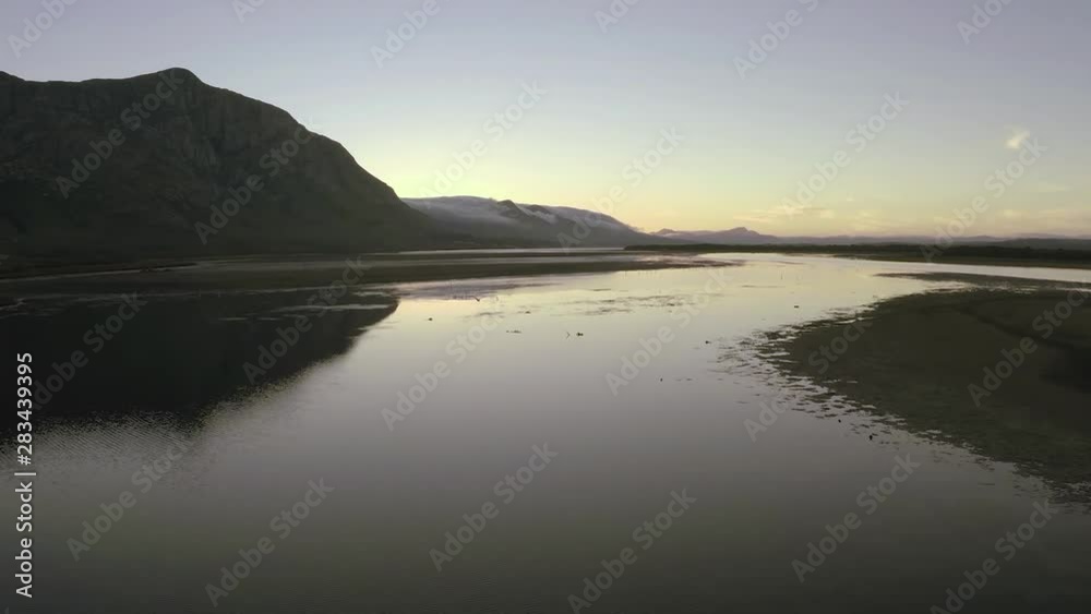 Coastal wetlands in Hermanus, South Africa at dawn. The mountains and sunrise sky are reflected in the placid water. Coastal wetlands in Hermanus, South Africa at dawn. The mountains and sunrise sky are reflected in the placid water.