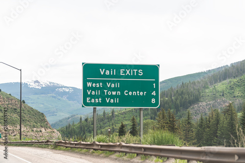 Vail road highway through Colorado towns with sign for exits in rocky mountains with town center