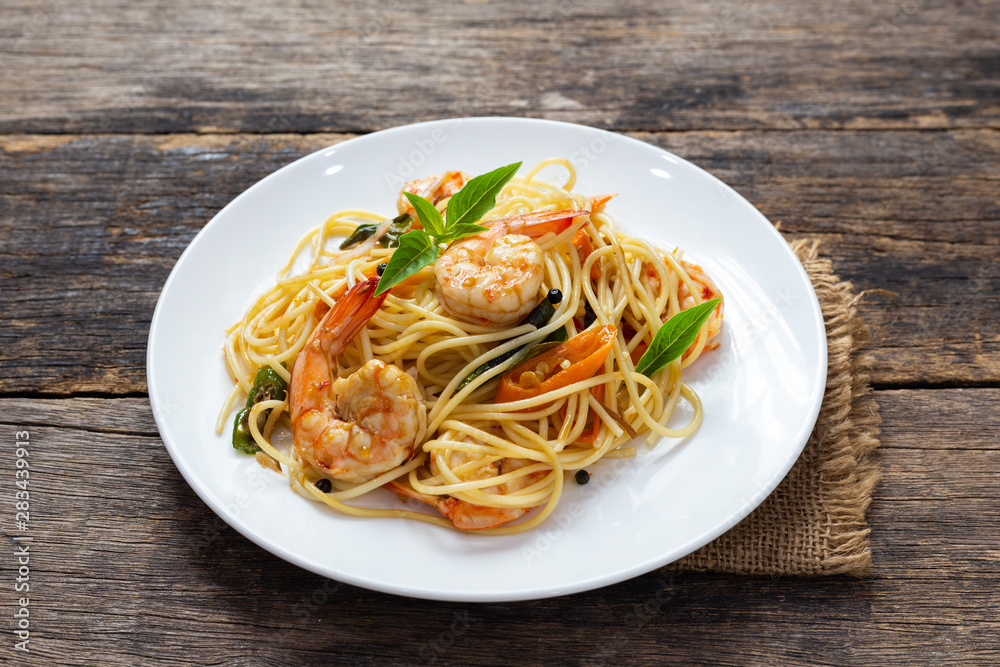 Spaghetti with spicy fried shrimp on a wooden table