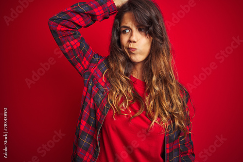 Young beautiful woman wearing casual jacket standing over red isolated background smiling with hands on chest with closed eyes and grateful gesture on face. Health concept.