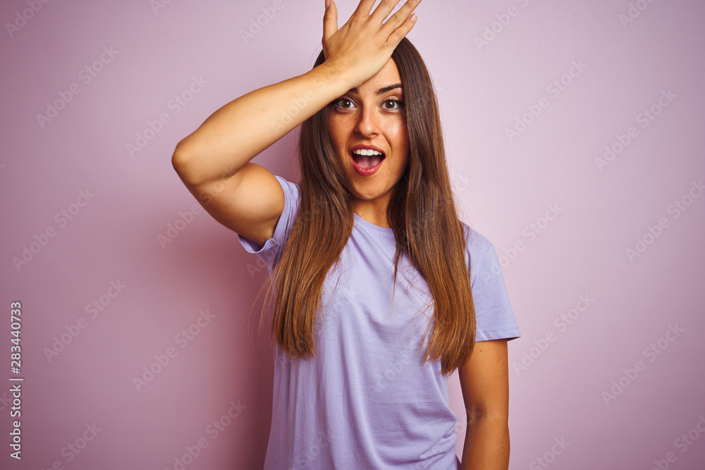 Young beautiful woman wearing casual t-shirt standing over isolated pink background surprised with hand on head for mistake, remember error. Forgot, bad memory concept.