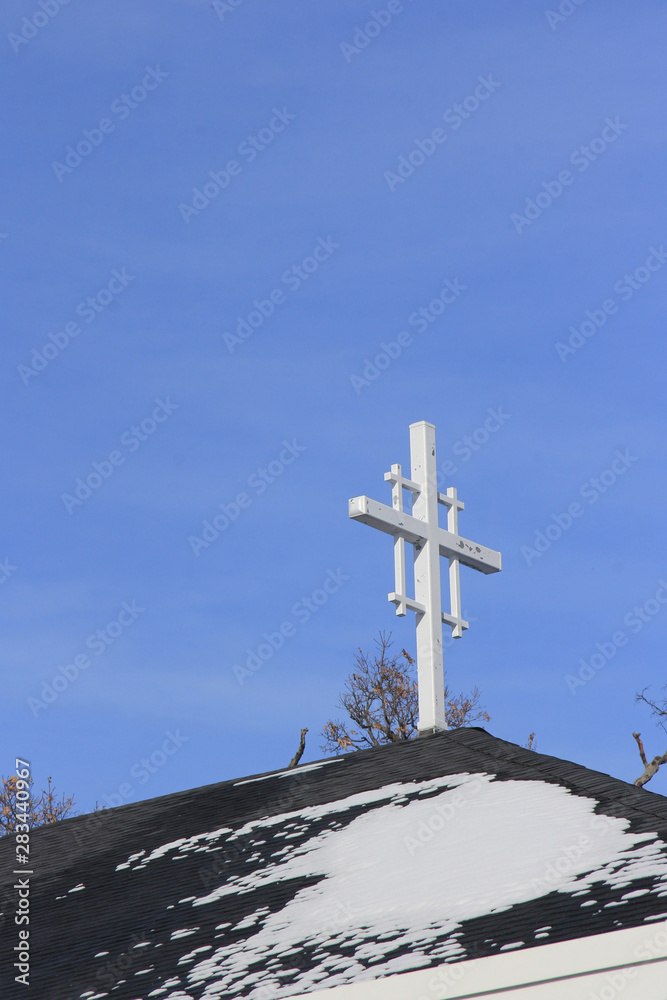 White crosss with a blue sky background on top of a steeple. White crosss with a blue sky background on top of a steeple.