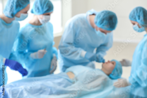 Plastic surgeons operating patient in clinic  blurred view