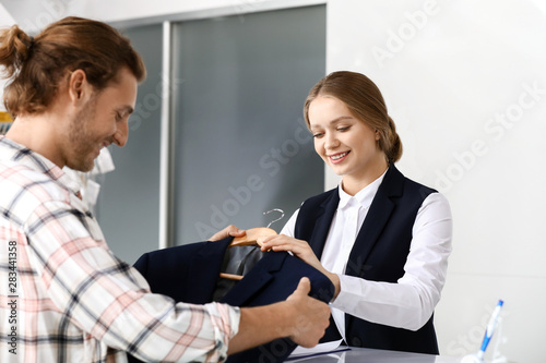 Worker of modern dry-cleaner's taking order from client at reception