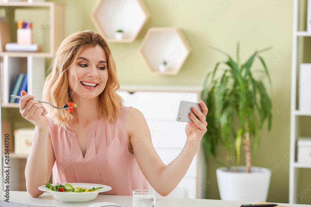 Woman taking selfie while eating healthy vegetable salad in office Woman taking selfie while eating healthy vegetable salad in office