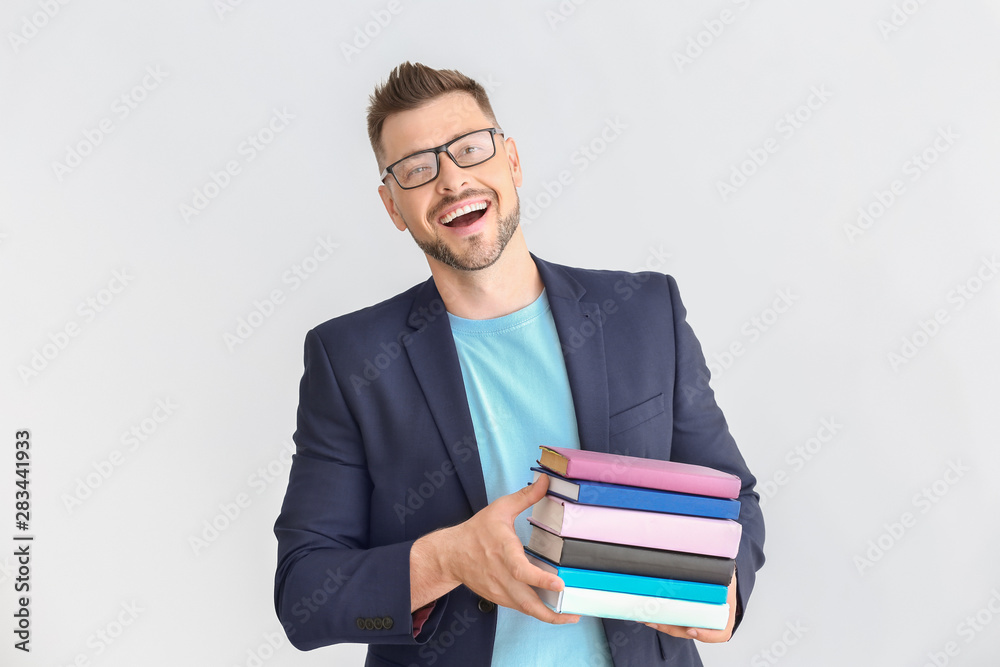 Handsome male teacher with books on light background Handsome male teacher with books on light background