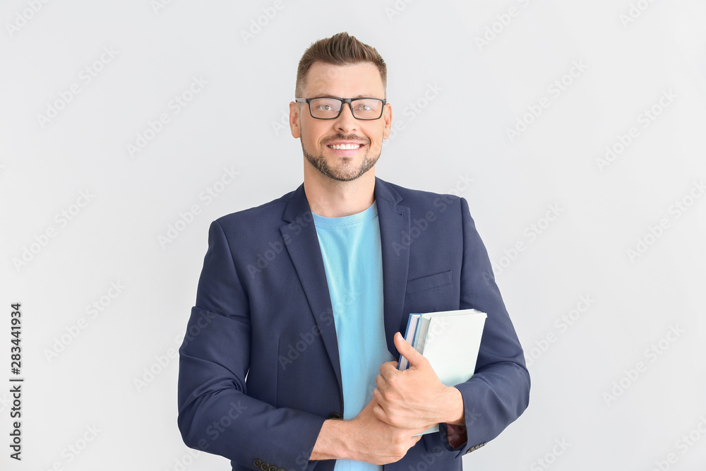 Handsome male teacher with books on light background Handsome male teacher with books on light background