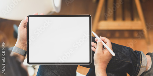 Young male freelancer holding blank screen tablet