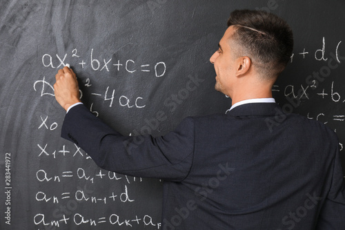Handsome math teacher writi...