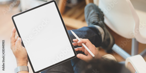 Young male freelancer reading and holding blank screen tablet photo