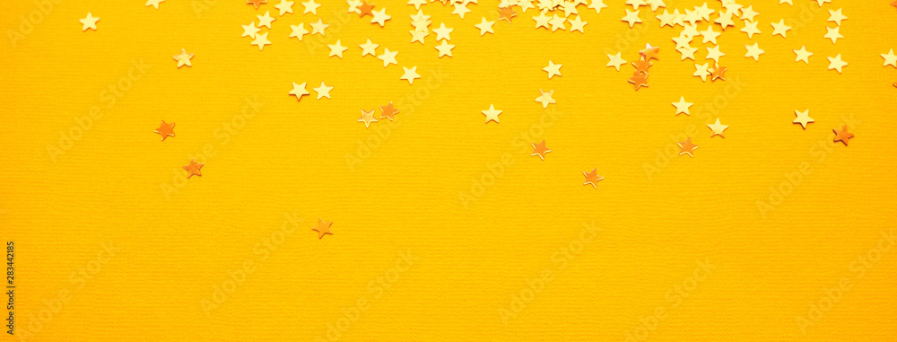 Golden stars glitter on yellow paper background Golden stars glitter on yellow paper background